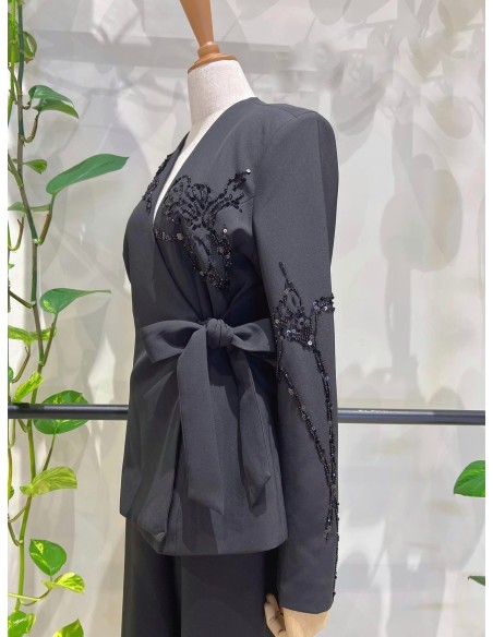 Traje de chaqueta compuesto por chaqueta entallada con lazada combinado con pantalón palazzo. Detalle de pedrería en ambas pieza
