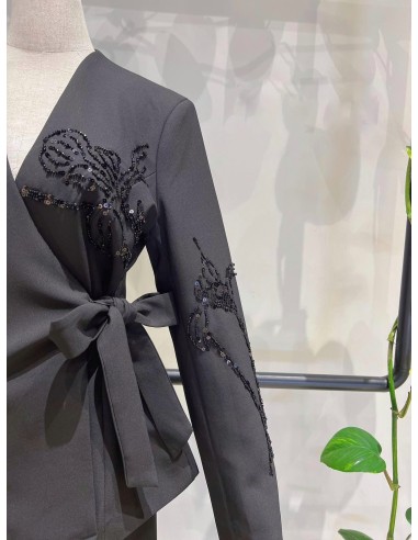 Traje de chaqueta compuesto por chaqueta entallada con lazada combinado con pantalón palazzo. Detalle de pedrería en ambas pieza