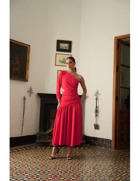 Vestido asimétrico de una sola manga con hombro pronunciado. Con Abertura lateral y falda con vuelo terminada con un gran volant