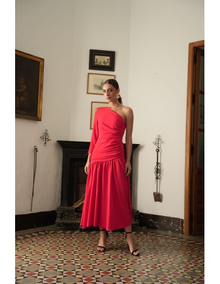 Vestido asimétrico de una sola manga con hombro pronunciado. Con Abertura lateral y falda con vuelo terminada con un gran volant