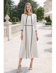 Vestido de corte midi en crepe elástico blanco y negro. Es de corte evasé, tiene cuello a la caja y mangas tres cuartos.
