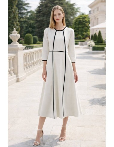 Vestido de corte midi en crepe elástico blanco y negro. Es de corte evasé, tiene cuello a la caja y mangas tres cuartos.