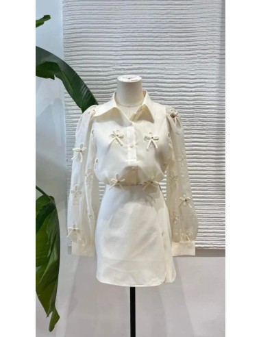 Camisa cuello camisero de lazos y pedrería con tejido fluido de manga larga. Cierre mediante botones delanteros.