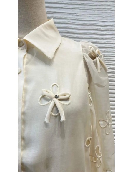 Camisa cuello camisero de lazos y pedrería con tejido fluido de manga larga. Cierre mediante botones delanteros.