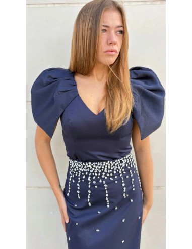 Top ajustado con cuello pico y mangas capa. Cierre mediante cremallera invisible trasera.