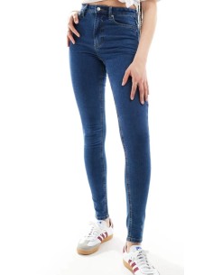 Jeans skinny fit de tiro alto con diseño de cinco bolsillos, cintura con trabillas, y cierre de botón y cremallera. 2