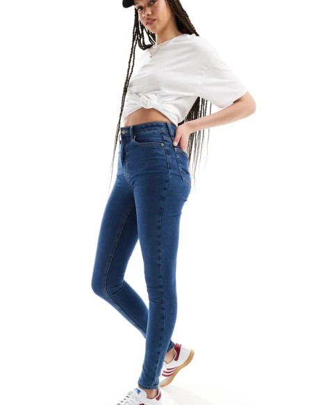Jeans skinny fit de tiro alto con diseño de cinco bolsillos, cintura con trabillas, y cierre de botón y cremallera.