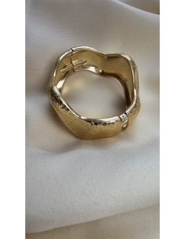 Brazalete metalizado con forma ondulada. Cierre con muelle.