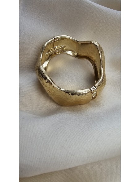 Brazalete metalizado con forma ondulada. Cierre con muelle.