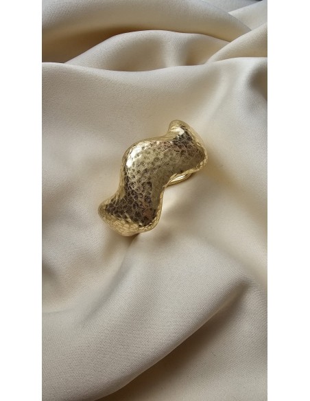 Brazalete metalizado con forma ondulada. Cierre con muelle.