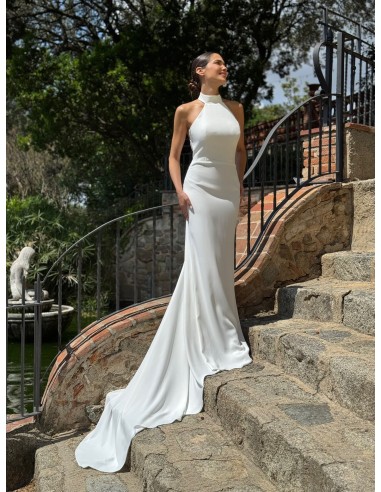 Vestido de cuello halter ajustado con espalda al aire y cola. Capa de vuelo volante con lazada en el cuello.