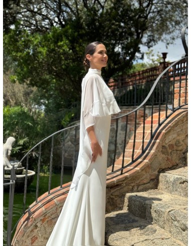 Vestido de cuello halter ajustado con espalda al aire y cola. Capa de vuelo volante con lazada en el cuello.