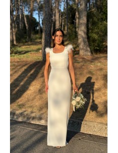 Vestido largo recto con tejido fluido y espalda al aire. Detalle de pedrería y plumas en el hombro. Cierre mediante botones forr
