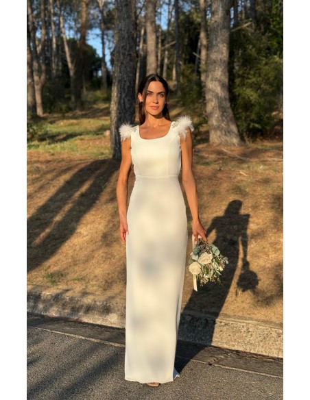 Vestido largo recto con tejido fluido y espalda al aire. Detalle de pedrería y plumas en el hombro. Cierre mediante botones forr