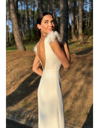 Vestido largo recto con tejido fluido y espalda al aire. Detalle de pedrería y plumas en el hombro. Cierre mediante botones forr