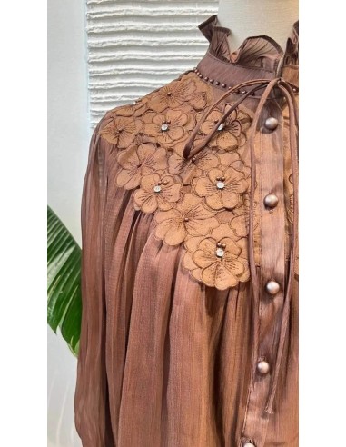 Camisa de manga larga en tejido fluido con detalle de flores bordadas en escote y puños. Cierre mediante botones nacarados y laz