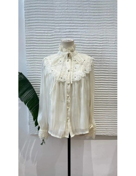 Camisa de manga larga en tejido fluido con detalle de flores bordadas en escote y puños. Cierre mediante botones nacarados y laz