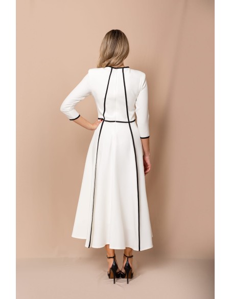 Vestido de corte midi en crepe elástico blanco y negro. Es de corte evasé, tiene cuello a la caja y mangas tres cuartos.