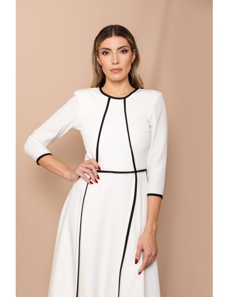 Vestido de corte midi en crepe elástico blanco y negro. Es de corte evasé, tiene cuello a la caja y mangas tres cuartos.